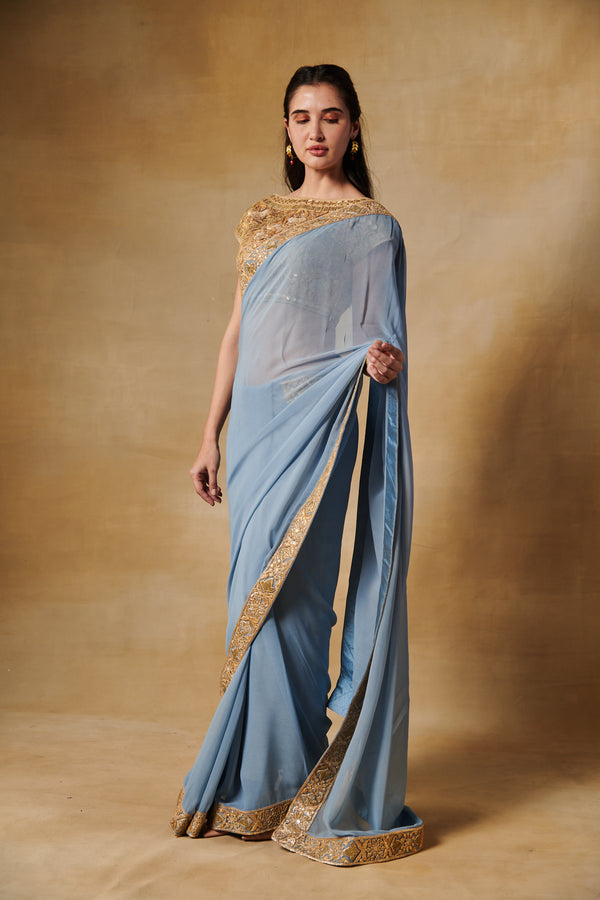 Powder blue georgette saree with all over gold blouse