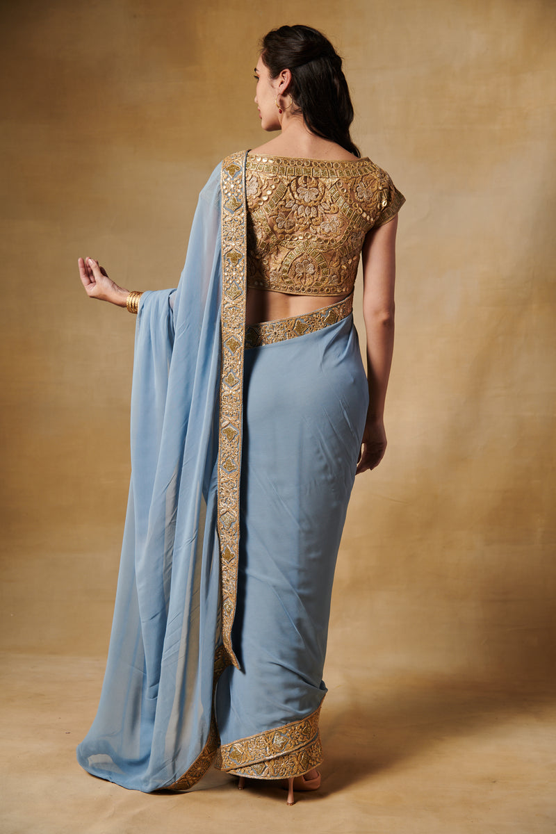 Powder blue georgette saree with all over gold blouse